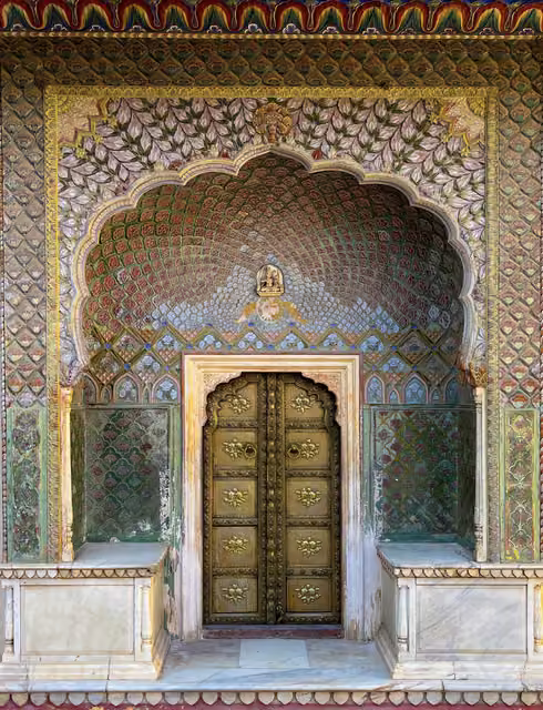 Ornate arched palace doorway with brass studded double doors, rose-patterned painted plasterwork, marble benches either side and stone floor
