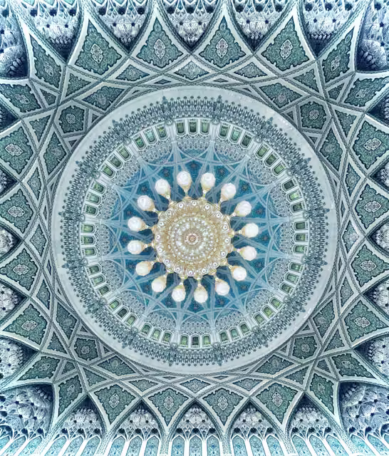 Upward view of a mosque dome: teal and white geometric tilework, arched clerestory windows, and a large gold crystal chandelier with sixteen radiating lamps.